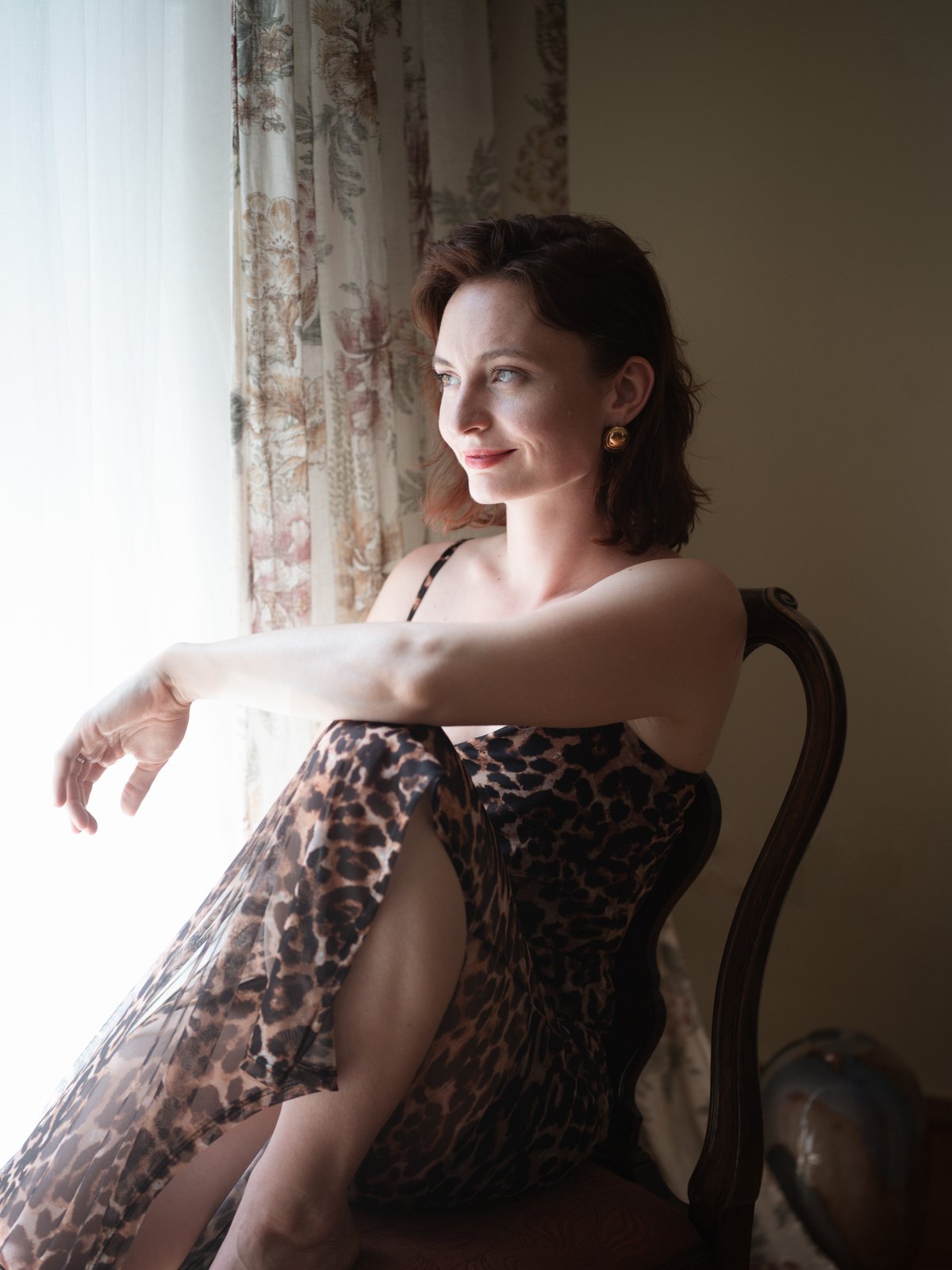 Daniela sitzt am Fenster im Leopardenkleid und lächelt