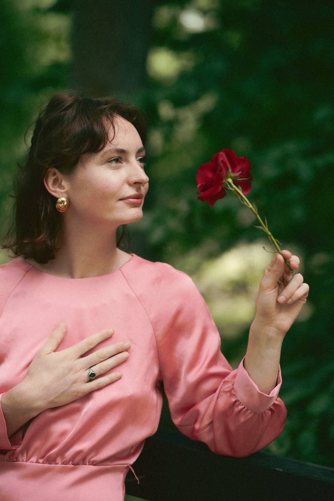 Daniela Taeger im rosa Seidenkleid, eine rote Rose in der Hand, die andere Hand auf dem Herzen